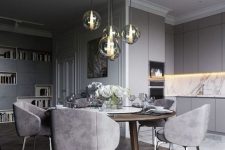 a refined and chic contemporary dining space with a stained round table, grey chairs, a cluster of pendant lamps
