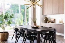 a refined mid-century modern dining room with a stained storage unit, a dark-stained table and black chairs, a printed rug and a gold chandelier