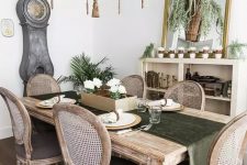 a refined rustic vintage dining room with a credenza, a large mirror, lots of greenery and an elegant stained dining set plus a vintage chandelier