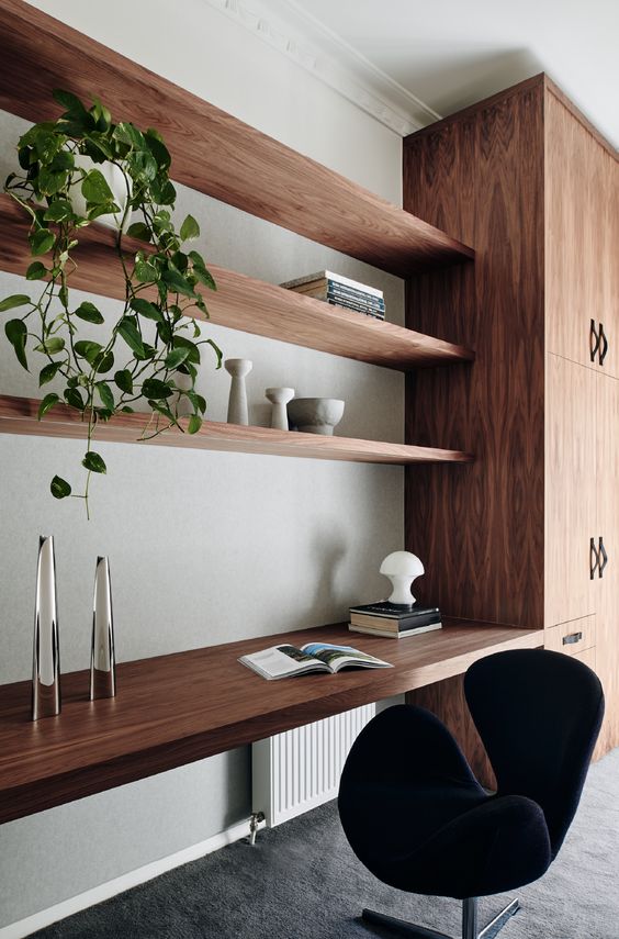 a relaxed contemporary home office with a strained storage unit, shelves and a floating desk, a black chair and a plant