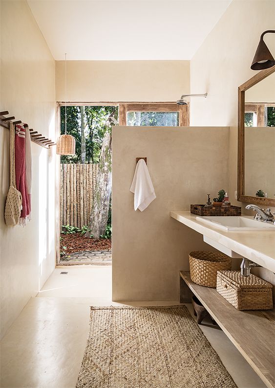 a relaxed indoor-outdoor bathroom with a shower space that is separates with a half wall from the rest of the space