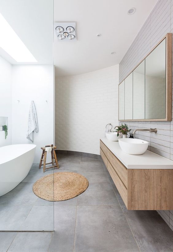 a serene contemporary bathroom clad with white tiles and concrete ones, a stained floating vanity and an oval bathtub