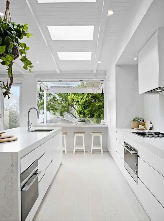 a serene white contemporary kitchen with sleek cabinets, a large kitchen island, white stone countertops and a backsplash