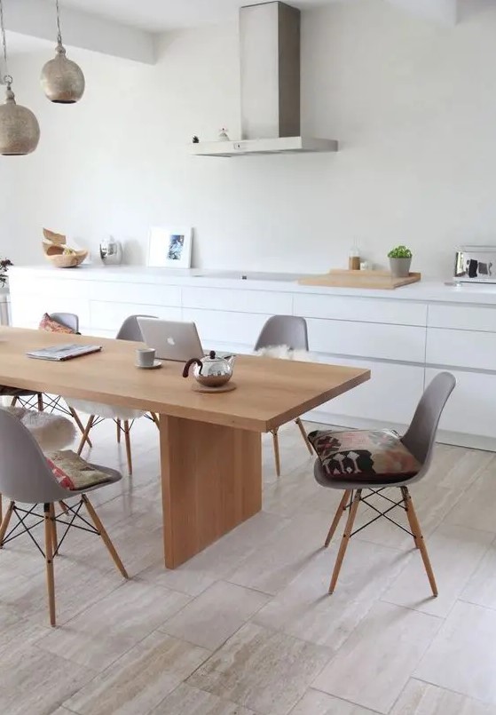 a sleek Nordic dining room with a light stained table and matching grey chairs plus metal pendant lamps