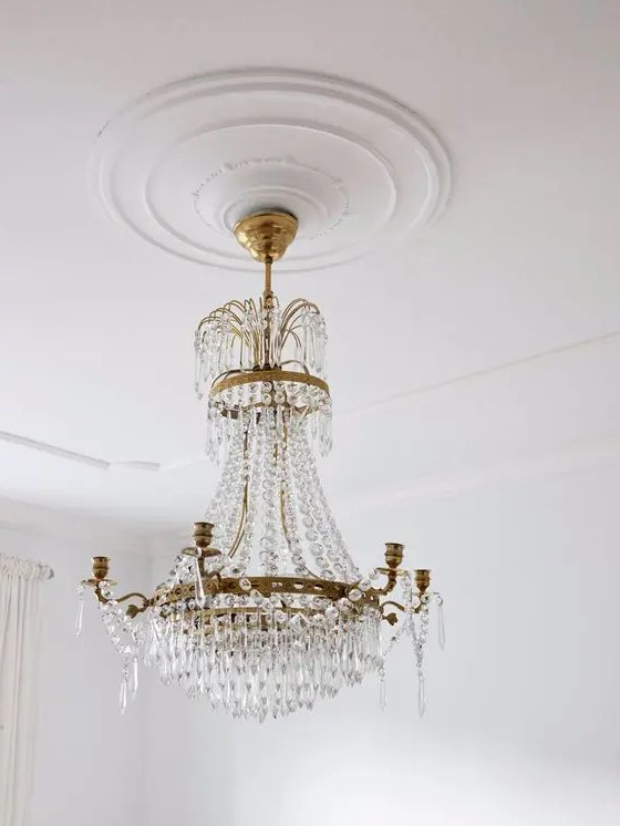 a sleek white ceiling medallion that accents a statement and oversized crystal and brass chandelier look wow together