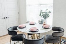 a small and cool dining space with a round table, black rounded chairs, a cool artwork and a printed neutral rug is welcoming