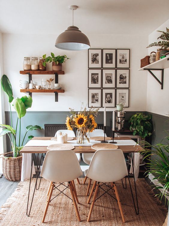 a small and cozy dining room with a hairpin leg table, white Eames chairs, shelves with plants and a grid gallery wall