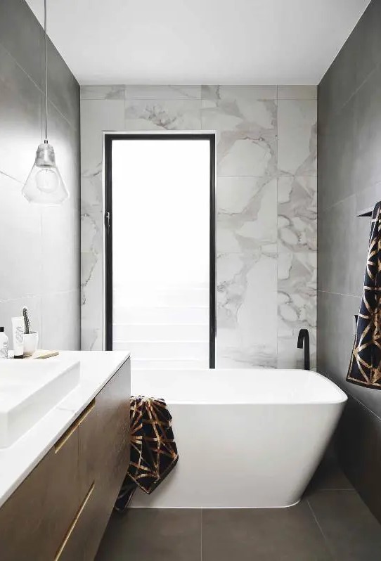 a small contemporary bathroom with a tub, a frosted glass window, a floating vanity and a square sink, pendant lamps