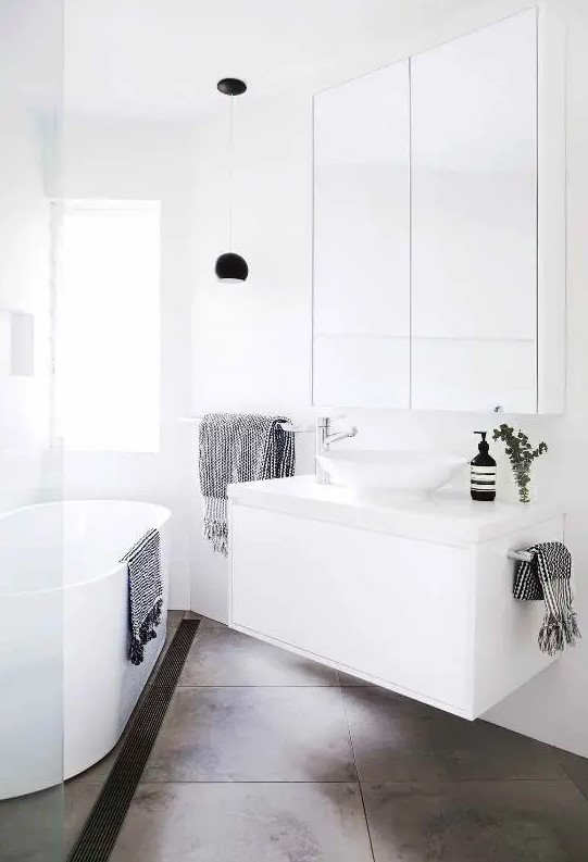a small contemporary bathroom with a tub, a white floating vanity and a round sink, a large mirror and a shower
