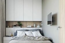 a small contemporary bedroom with sleek white storage units, an upholstered bed and a small nightstands, neutral bedding is chic