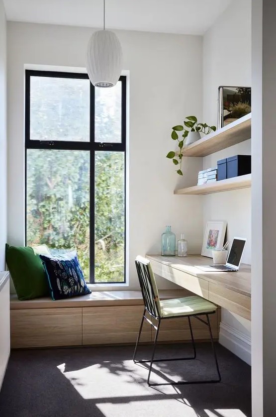 a small contemporary home office with a sleek storage daybed by the window, a floating desk, floating shelves and touches of green