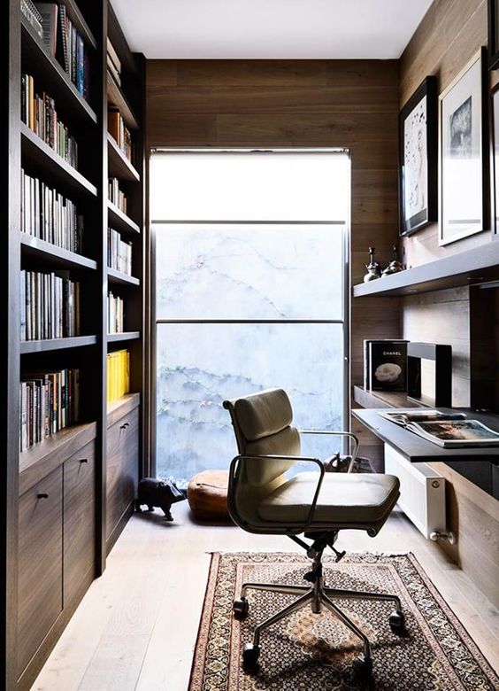a small contemporary home office with built-in bookcases, a floating desk and a shelf, a rug and a comfy chair