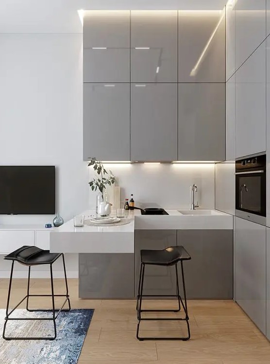 a small contemporary kitchen with sleek grey cabinets, a white floating countertop and a backsplash, some built-in appliances
