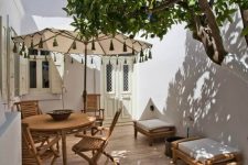 a small terrace clad with tiles, with wooden folding furniture, a couple of stools and an umbrella is very cozy and welcoming