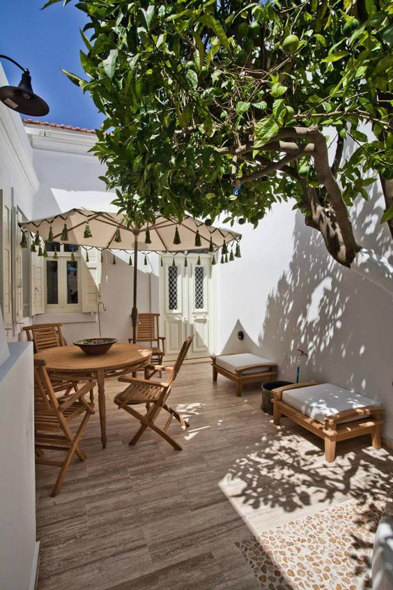 a small terrace clad with tiles, with wooden folding furniture, a couple of stools and an umbrella is very cozy and welcoming