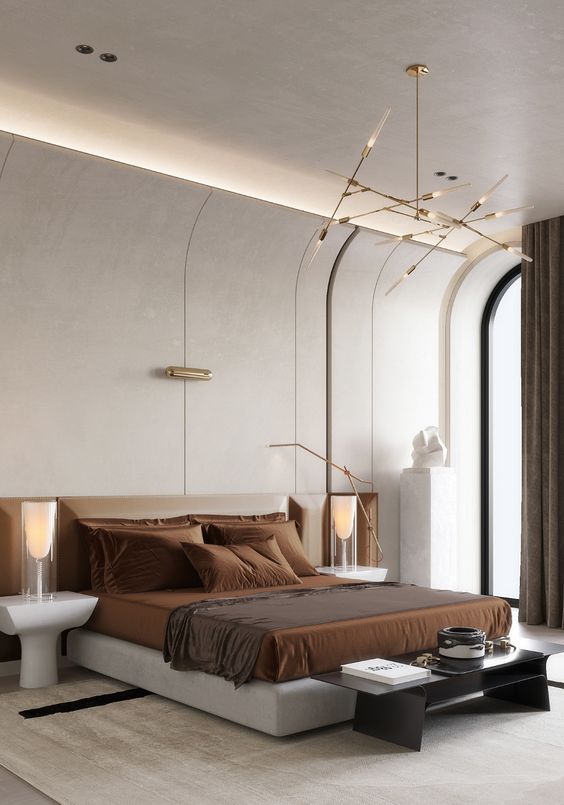 a sophisticated contemporary bedroom with a curved wall and built-in lights, an upholstered bed with rust bedding, a bench and catchy nightstands