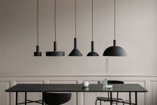 a sophisticated greige dining room with chic walls, a black dining table and chairs and a cluster of black pendant lamps