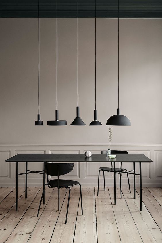 a sophisticated greige dining room with chic walls, a black dining table and chairs and a cluster of black pendant lamps