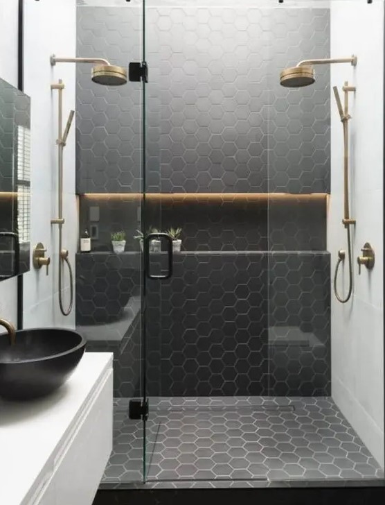 a stylish contemporary bathroom with white square tiles and black hex ones plus brass touches and fixtures