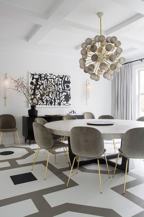 a stylish contemporary dining room with a round table, grey chairs, a globe chandelier, a black and white artwork