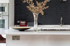 a stylish contemporary white kitchen with a black brick backsplash, pendant bulbs and touches of gold is chic and bold