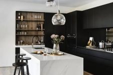a stylish contrasting kitchen with sleek black cabinets, a white stone kitchen island, built-in shelves and a cluster of pendant lamps