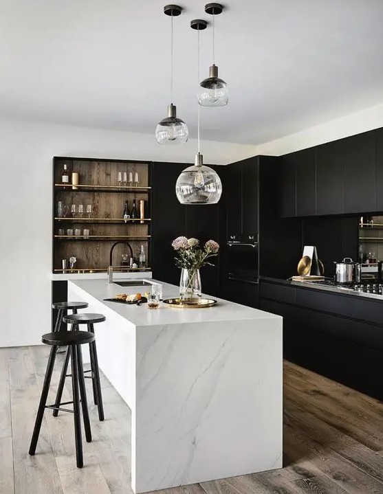 a stylish contrasting kitchen with sleek black cabinets, a white stone kitchen island, built in shelves and a cluster of pendant lamps