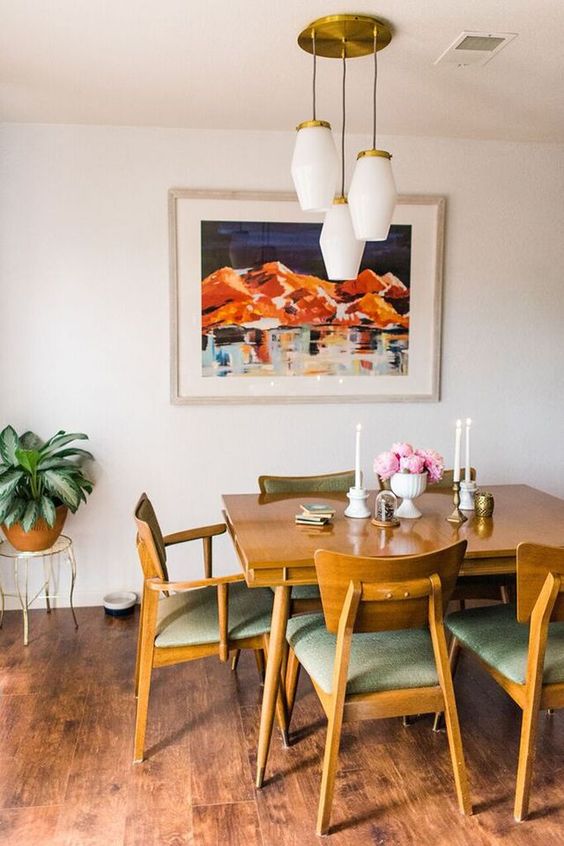 a stylish mid century modern dining room with a stained table and matching chairs, a cluster of pendant lamps and candles