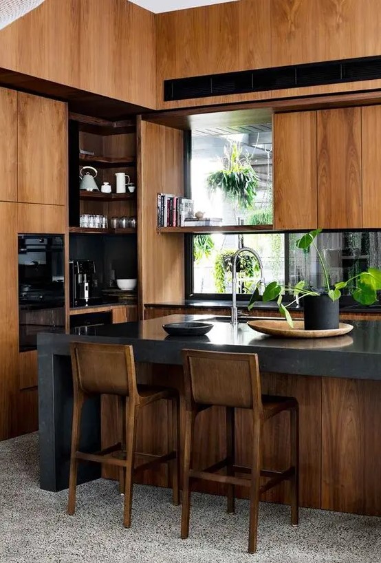 a stylish modern stained kitchen with black countertops, windows instead of a backsplash and a grey stone kitchen island