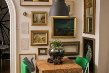 a tiny and bold dining nook with a vintage artwork gallery wall, a cool table and emerald chairs, a black pendant lamp