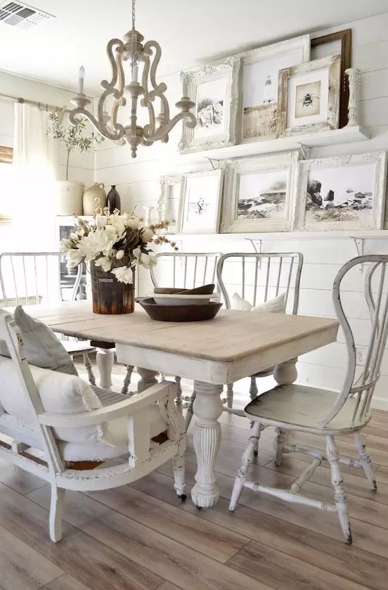 a vintage dining room with white shiplap walls, mismatched furniture, a large gallery wall and a vintage chandelier