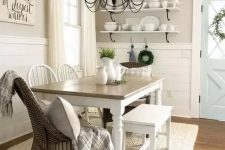 a vintage farmhouse dining nook with open shelves, a wooden table, wooden and wicker chairs and a metal chandelier