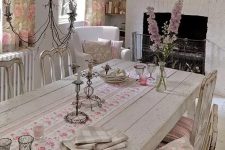 a vintage neutral dining room with wooden furniture, a fireplace, pink floral textiles and a vintage chandelier