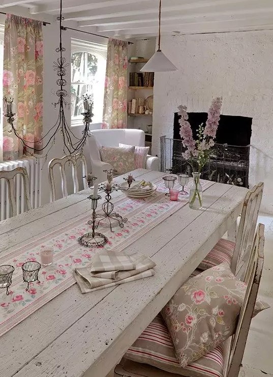 a vintage neutral dining room with wooden furniture, a fireplace, pink floral textiles and a vintage chandelier