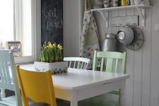 a vintage neutral dining space with shelves on the wall, a white table and mismatching chairs, pastel floral prints and a chalkboard to leave notes