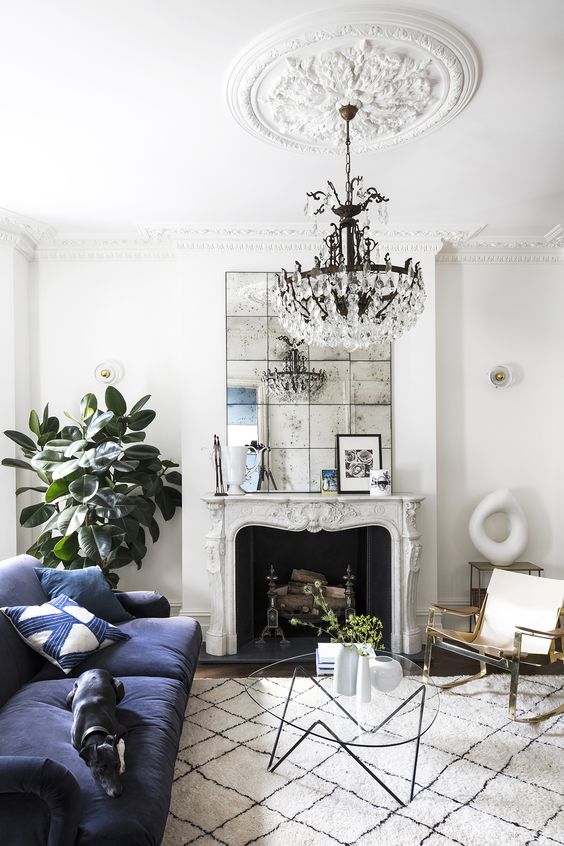 a vintage neutral space accented with a large and chic ceiling medallion, with a bold blue sofa and a vintage non-working fireplace