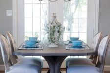 a vintage rustic dining zone with a stained dining table, upholstered chairs, a vintage metal chandelier and a beautiful lantern with greenery