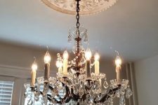 a white ceiling medallion paired with a crystal chandelier, with candles and crystals hanging down for adding vintage chic to the space