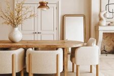 an elegant and chic neutral dining room with a stained table, neutral chairs, a fireplace clad with brick, a floor mirror and a very stylish pendant lamp