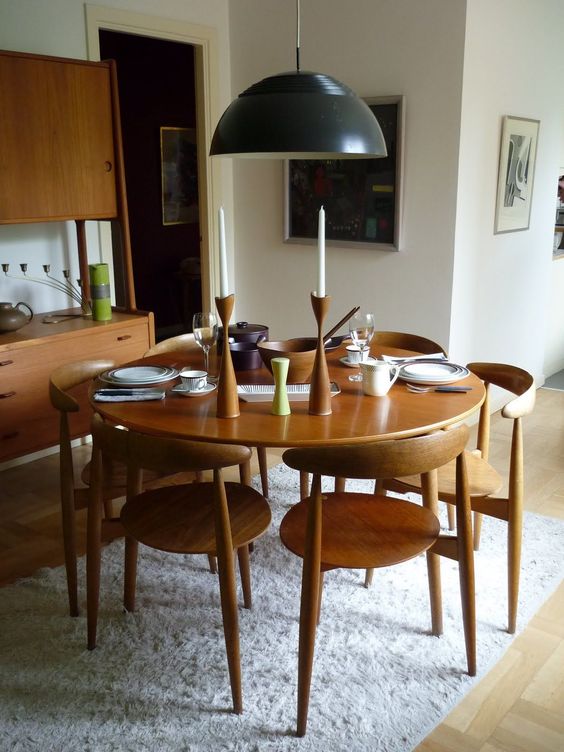 an elegant mid century modern dining room with a stained table and chairs, matching storage cabinets, a black pendant lamp