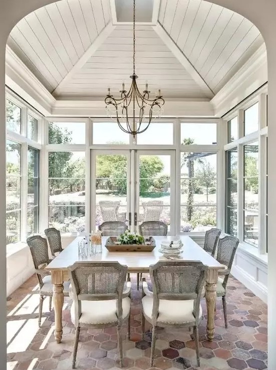 an elegant vintage sunroom dining space with stylish rattan chairs and a large table is great