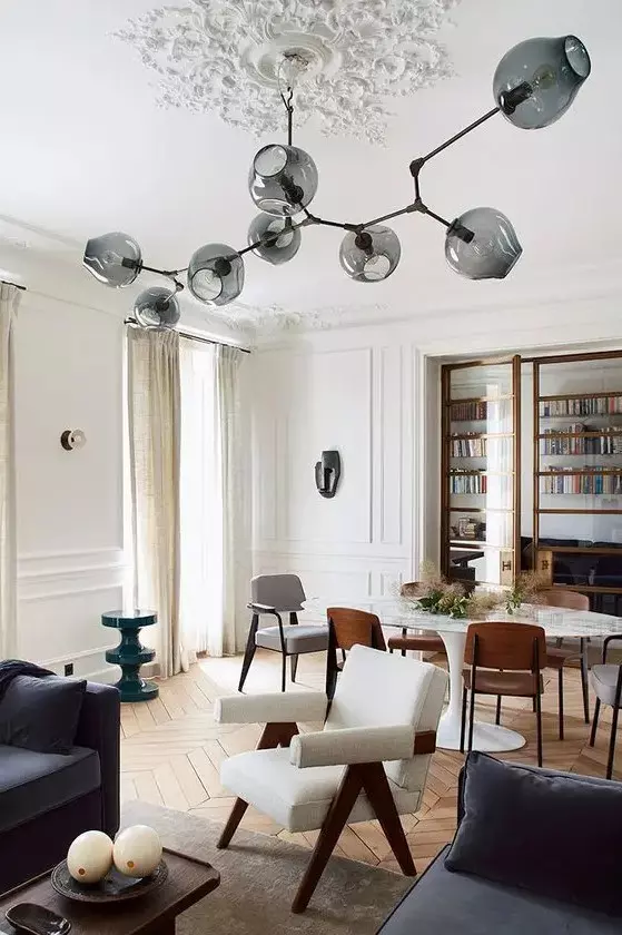 an oversized beautiful ceiling medallion formed of pieces attached right to the ceiling and a stylish mid-century modern chandelier with smoked glass