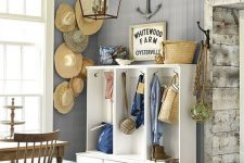 02 a beach cottage space with grey walls, a hat display on the wall, a white storage unit, stained furnture and a striped pouf