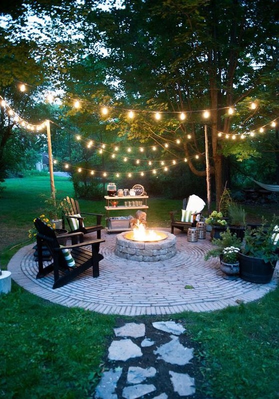 a backyard fire pit with string lights over the space is warm and welcoming and looks very cool