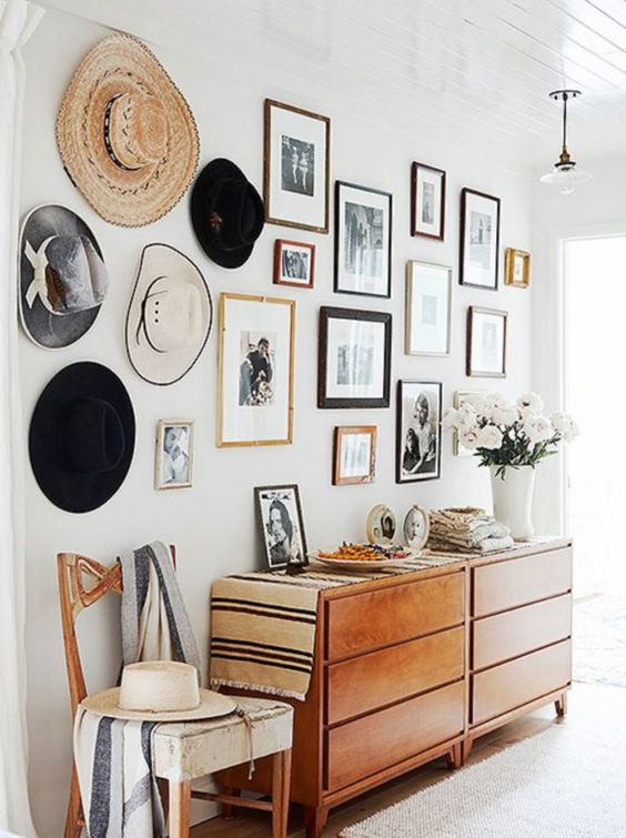 a beautiful gallery wall of photos and hats that create a single and cohesive color scheme and look very nice
