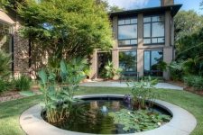 04 a modern outdoor space with grene lawn and a small round pond with water plants for more eye-catchiness and a soothing feel