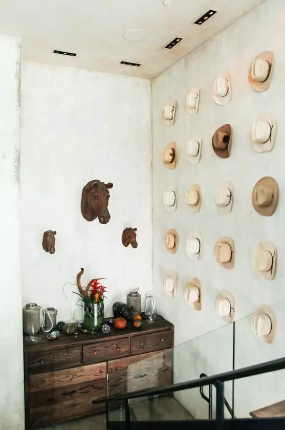 a blank wall over the staircase is done with hats that add interest to the space and lets your display your accessories at their best