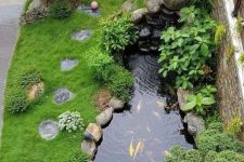 08 a small zen-inspired outdoor space with green lawn, rocks and pebbles, with a small pond with koi fish and greenery around it