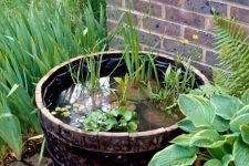 10 a barrel water garden with greenery and rocks and green plants around for a natural touch in your garden
