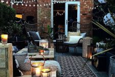 17 a welcoming backyard with pallet and rattan furniture, with printed textiles, candle lanterns and string lights over the space